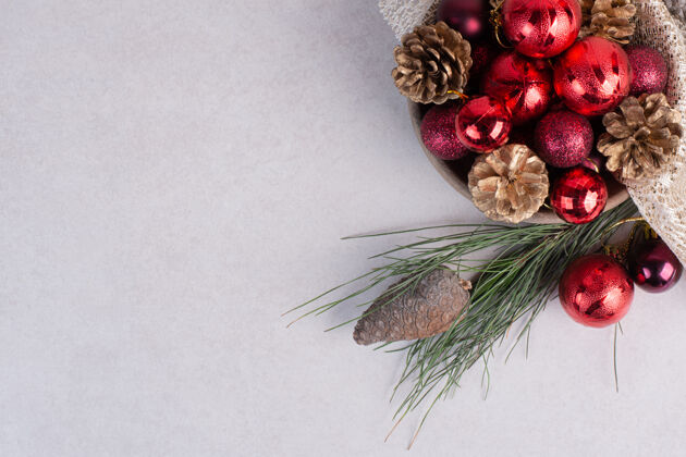 庆祝麻布上放着圣诞红球和松果的木盘木红平