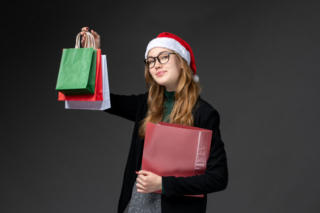 视图正面图：年轻女性 黑色墙上有包装礼品新年圣诞礼物笔记本电脑微笑圣诞节