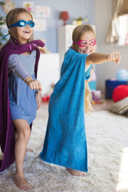 超级英雄小女孩们假装的女超级英雄享受毛巾地毯