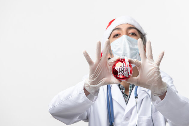 医院正面图男医生戴着口罩和玩具在白墙上健康共舞新年病毒病毒圣诞节服装