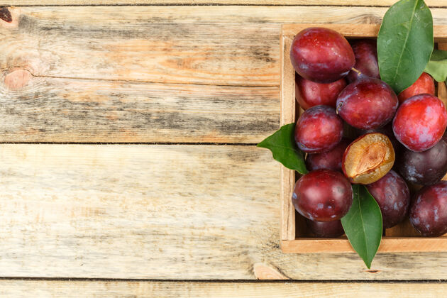 浆果李子在一个木箱在一个木板背景顶视图为您的文字自由空间饮食素食主义者新鲜