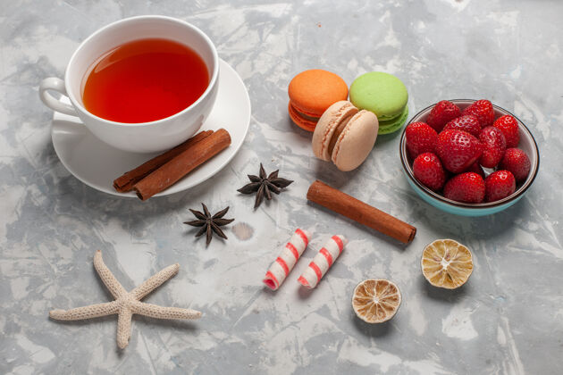 水果在白色的桌子上放上一杯新鲜草莓和法式马卡龙茶烘焙麦卡龙草莓
