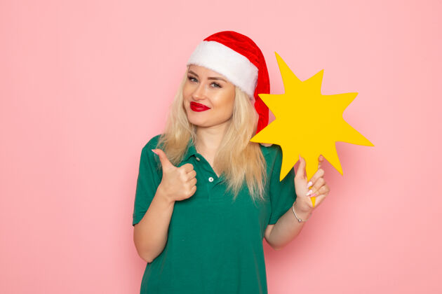 身材正面图年轻女性手持粉色墙壁上的黄色大人物度假照片新年快递员制服工作圣诞节工作肖像