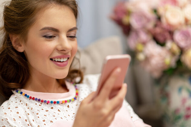 特写快乐的年轻女人在家里看着她的智能手机女人在她的智能手机上输入信息室内沟通房间