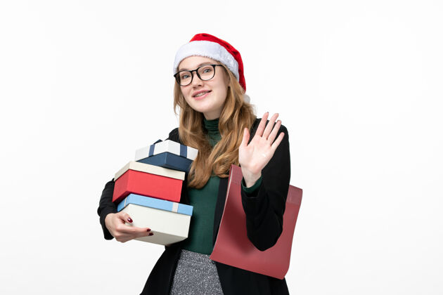 秘书正面图年轻女性手持节日礼物在白墙书上上课圣诞节微笑课程