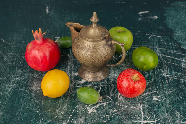 苹果混合新鲜水果和经典茶壶放在大理石桌上橘子混合飞珠