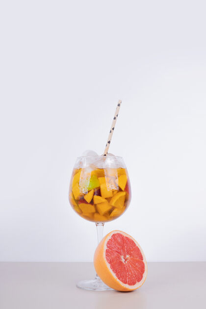 稻草一杯白墙上有水果片和葡萄柚的果汁葡萄柚冰饮料