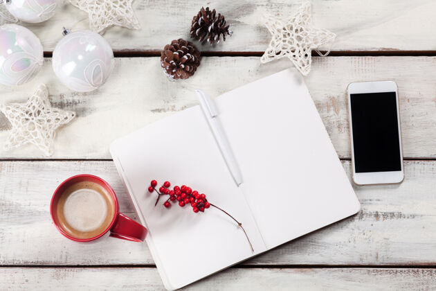电话打开木制桌上的笔记本 上面放着电话和圣诞装饰品传统床单庆祝