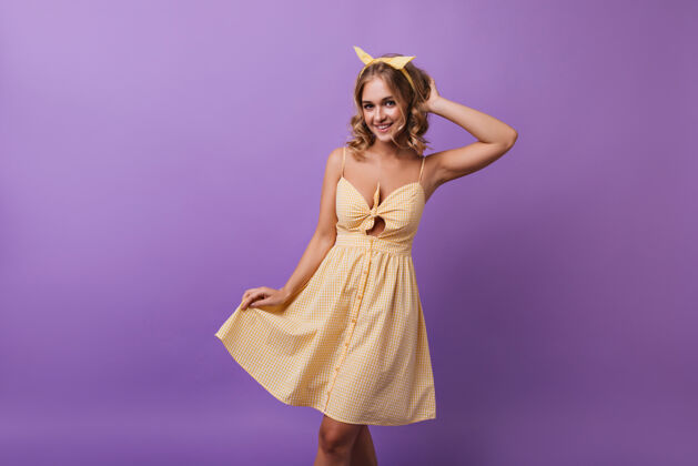 瘦身可爱的女模特穿着黄色格子裙微笑着跳舞美丽的金发女孩享受美好的一天紫色快乐明亮