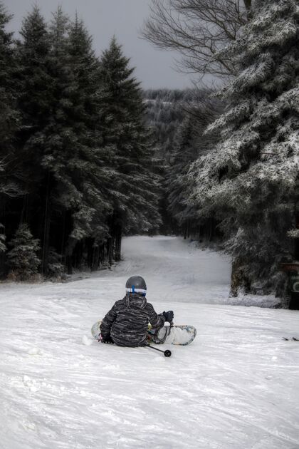 人一个人穿着滑雪板坐在山上的垂直镜头季节休闲户外