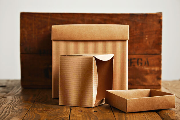 工厂一个打开 一个关闭米色纸箱旁边的一个乡村棕色木箱隔离在白色交货纸箱材料