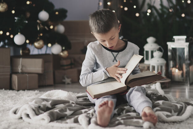 圣诞节地板上放着一本魔法书的男孩庆祝房间图片