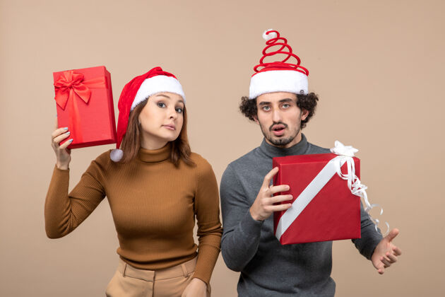 心情新年气氛和派对理念的俯瞰图-迷茫可爱的情侣拿着礼物戴着圣诞老人的灰色帽子礼物上衣圣诞