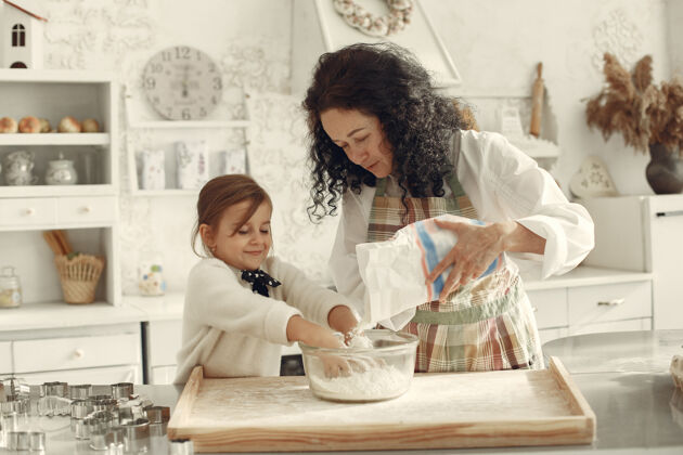 女人厨房里的人奶奶带着小女儿成年妇女教小女孩做饭帮助厨师面包店