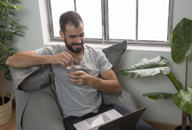 工作笑脸男在家里用笔记本电脑喝咖啡家庭职业水平