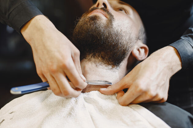 年轻有胡子的男人有客户的理发师刮胡子的男人理发师犀利时尚
