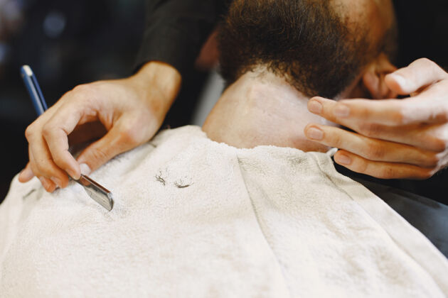 头有胡子的男人有客户的理发师刮胡子的男人室内剪商店