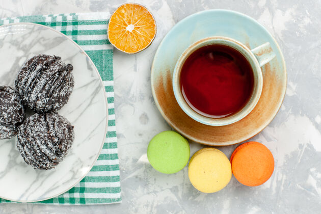 茶俯瞰美味的巧克力球圆形蛋糕加冰茶和麦卡龙在浅白的桌子上烤蛋糕巧克力糖派甜巧克力球热的