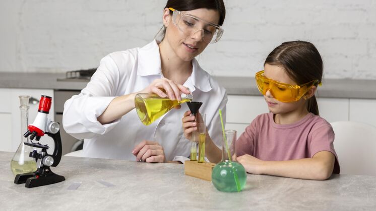 安全小女孩和女老师用显微镜和试管做科学实验孩子科学家试管