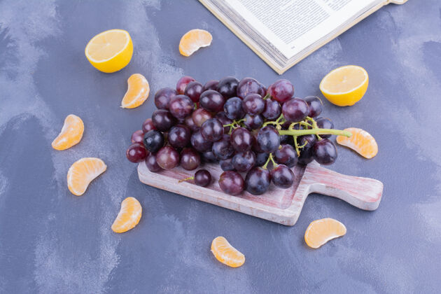 水果一大串红葡萄放在木盘上 周围是柑桔美味成分多汁