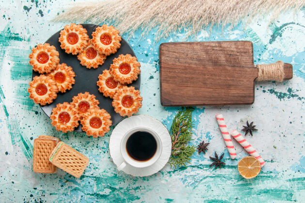 少量俯瞰美味的小饼干与华夫饼和咖啡杯上的蓝色办公桌饼干饼干甜甜的糖色茶颜色饼干早餐
