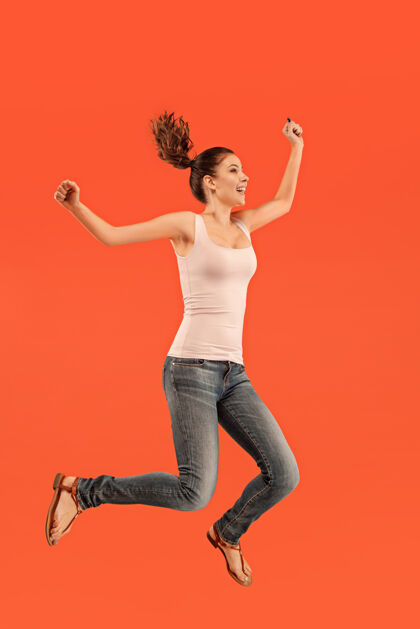 模特在移动中的自由相当快乐的年轻女子跳跃的半空中拍摄成人舞蹈服装