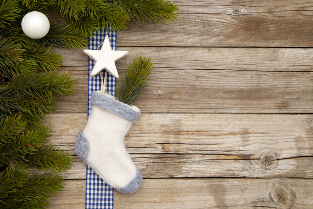 礼物圣诞装饰品的俯视图和一只放在木头桌子上的袜子 上面有树枝节日袜子装饰