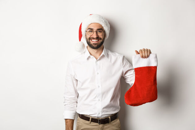 兴奋圣诞快乐 节日概念快乐的成年人收到礼物在圣诞节袜子 看起来很兴奋 戴着圣诞帽情绪化成人节日