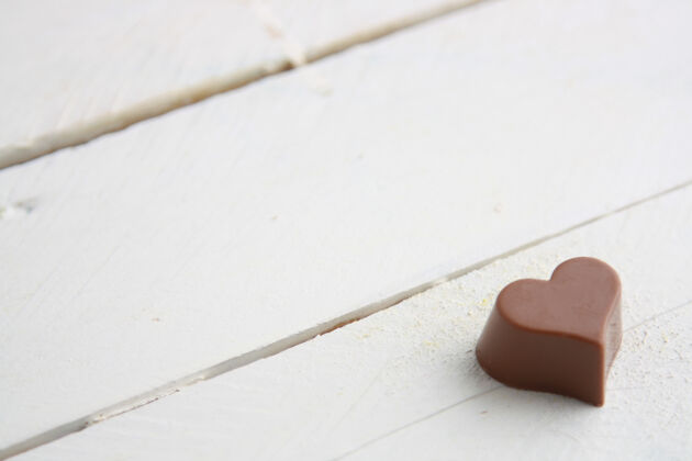 吃一张白色木桌上的心形巧克力糖特写镜头木制圣诞节生日