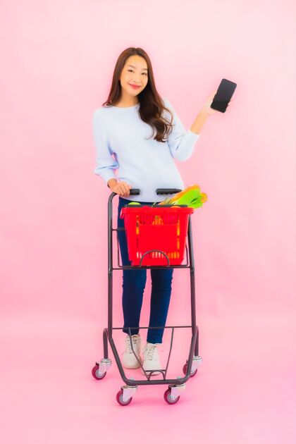 肖像一幅美丽的亚洲年轻女子的画像 粉红色的隔离墙上 篮子里放着水果蔬菜和杂货篮子女人蔬菜