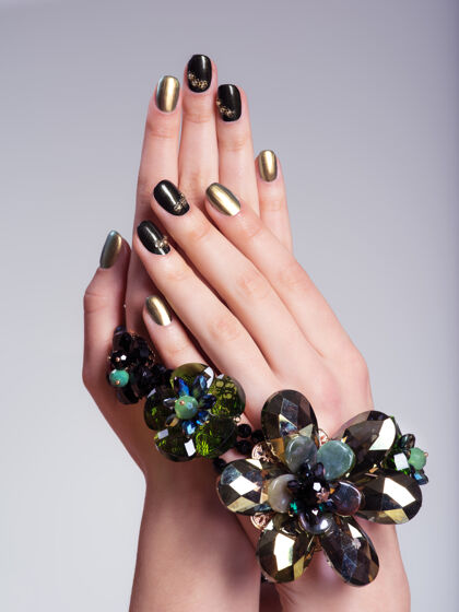 手美丽女人的指甲与创意美甲和珠宝指甲图案玻璃