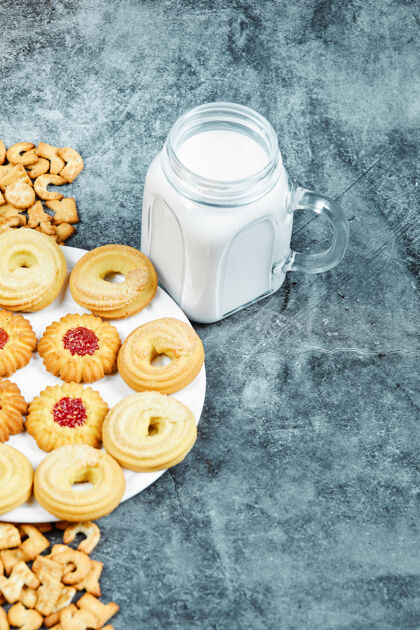 饼干散落的字母饼干 一盘饼干和一罐牛奶放在大理石桌上字母表美味棕色