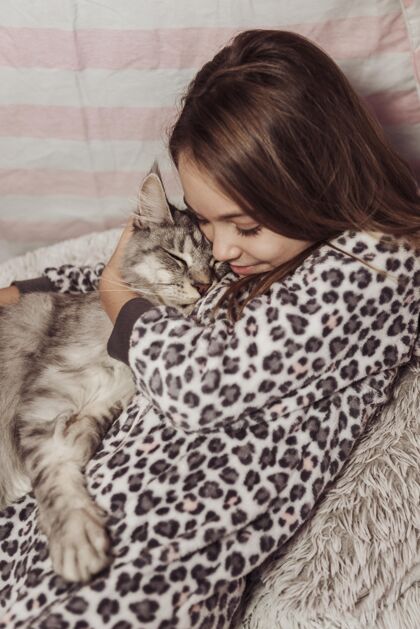 友谊穿着睡衣的女孩抱着她的毛茸茸的猫猫朋友快乐