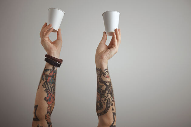 餐两个残暴的纹身男子双手拿着白纸带走纸杯呈现隔离在白色上早餐表面外卖