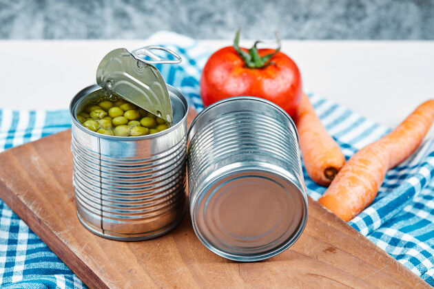 美味两罐煮青豌豆 蔬菜和桌布放在一张白色和大理石的桌子上罐头堆食品