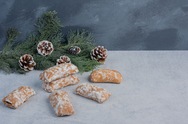 糖饼干包装旁边的松枝和圆锥形大理石表面甜的树枝蛋卷