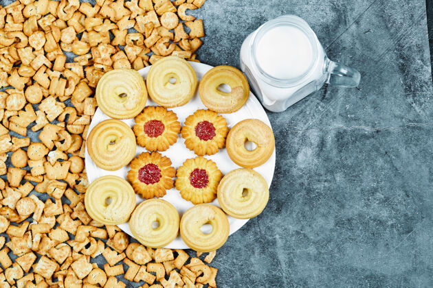 混合散落的字母饼干 一盘饼干和一罐牛奶放在大理石桌上视图顶部视图小吃