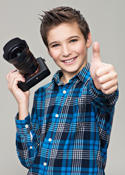 男孩男孩用相机拍照快乐有趣的男孩用单反相机显示拇指向上拍摄手势相机