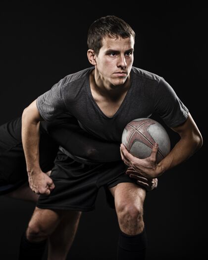 比赛男性橄榄球运动员用手臂持球的前视图冠军运动运动员