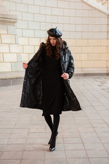 优雅时尚女人摆出冬秋时尚潮流黑色羽绒服和皮帽贝雷帽在古老美丽的街道穿着高跟鞋年轻城市服装