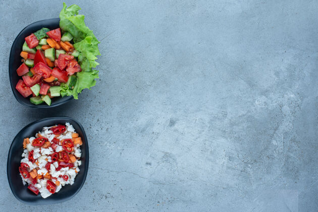 顶视图两碗羊肉沙拉和一碗胡椒和花椰菜沙拉放在大理石上生菜沙拉黄瓜