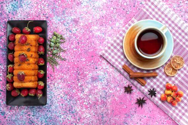 甜味顶视图美味的蛋糕与红色新鲜草莓和茶的粉红色背景糖蛋糕新鲜