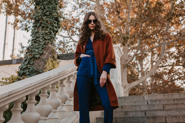 购物狂美丽时尚的微笑瘦身女子卷发走在街头楼梯上穿着温暖的棕色外套和蓝色西装 秋季时尚街头风蓝色包漂亮
