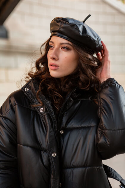 户外时尚女人摆出冬秋时尚潮流黑色羽绒服和皮帽贝雷帽在美丽老街优雅风格服装