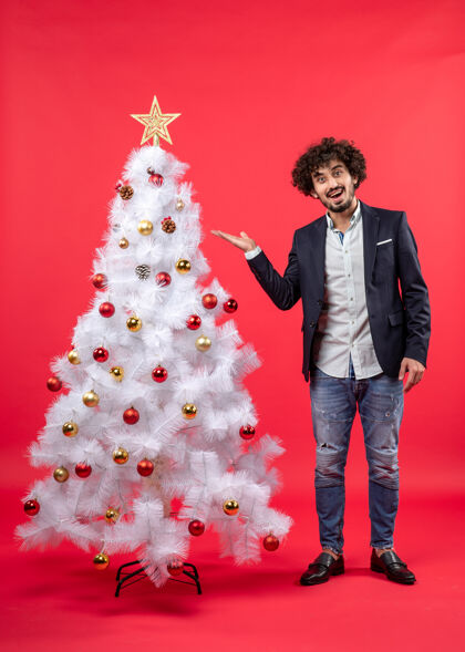 红色圣诞庆祝与胡子年轻人指着圣诞树年轻人节日圣诞树