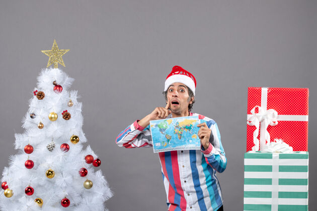 圣诞老人前视图有兴趣的男子与螺旋弹簧圣诞帽举行世界地图圣诞树可爱快乐