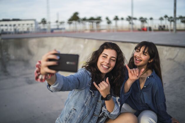 电话在溜冰场拍照的女孩们城市照片滑板