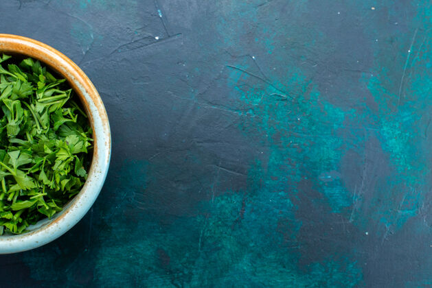 绿色在深蓝色桌子上的圆形锅里俯瞰新鲜的绿色欧芹新鲜香草
