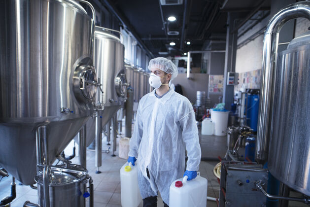 生产手握塑料罐的工业工人正准备在食品加工机中更换化学品实验室质量控制工程师