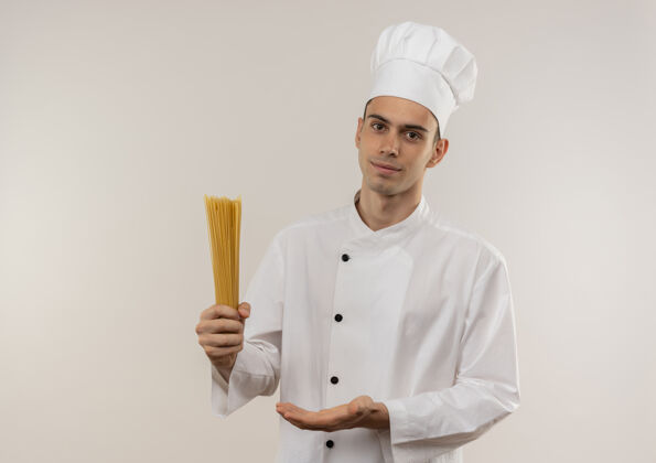 制服高兴的年轻男厨师穿着厨师制服显示意大利面在他的手与复制空间展示高兴男
